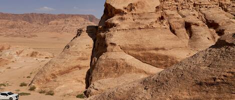 A desert landscape with rocky formations and a white vehicle.