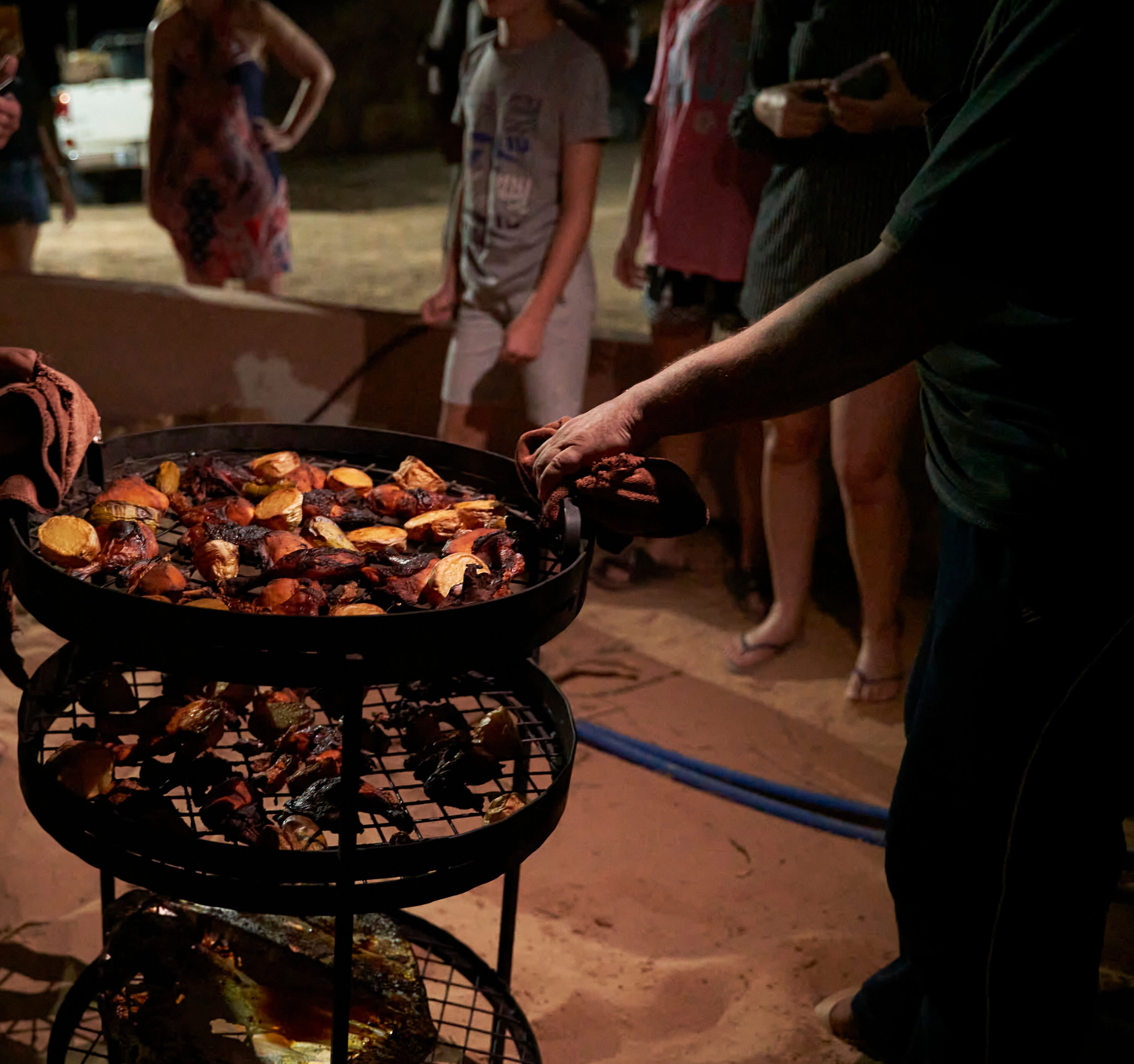 A person serving food from a grill with multiple cooking levels.