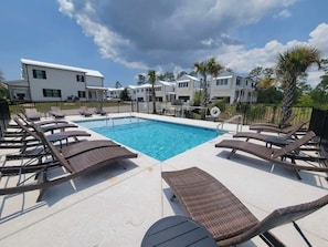 A swimming pool with lounge chairs and a white building in the background. - 10 Beds sleeps 16 with Arcade GAME ROOM & POOL! (Orange Beach)
