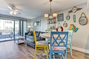 A modern living room with a sofa, chairs, a dining table, and a ceiling fan. - "Spritz By The Sea” is your beach side paradise! (Tybee Island)