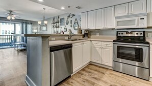 A modern kitchen with white cabinets, stainless steel appliances, and a wooden floor. - "Spritz By The Sea” is your beach side paradise! (Tybee Island)