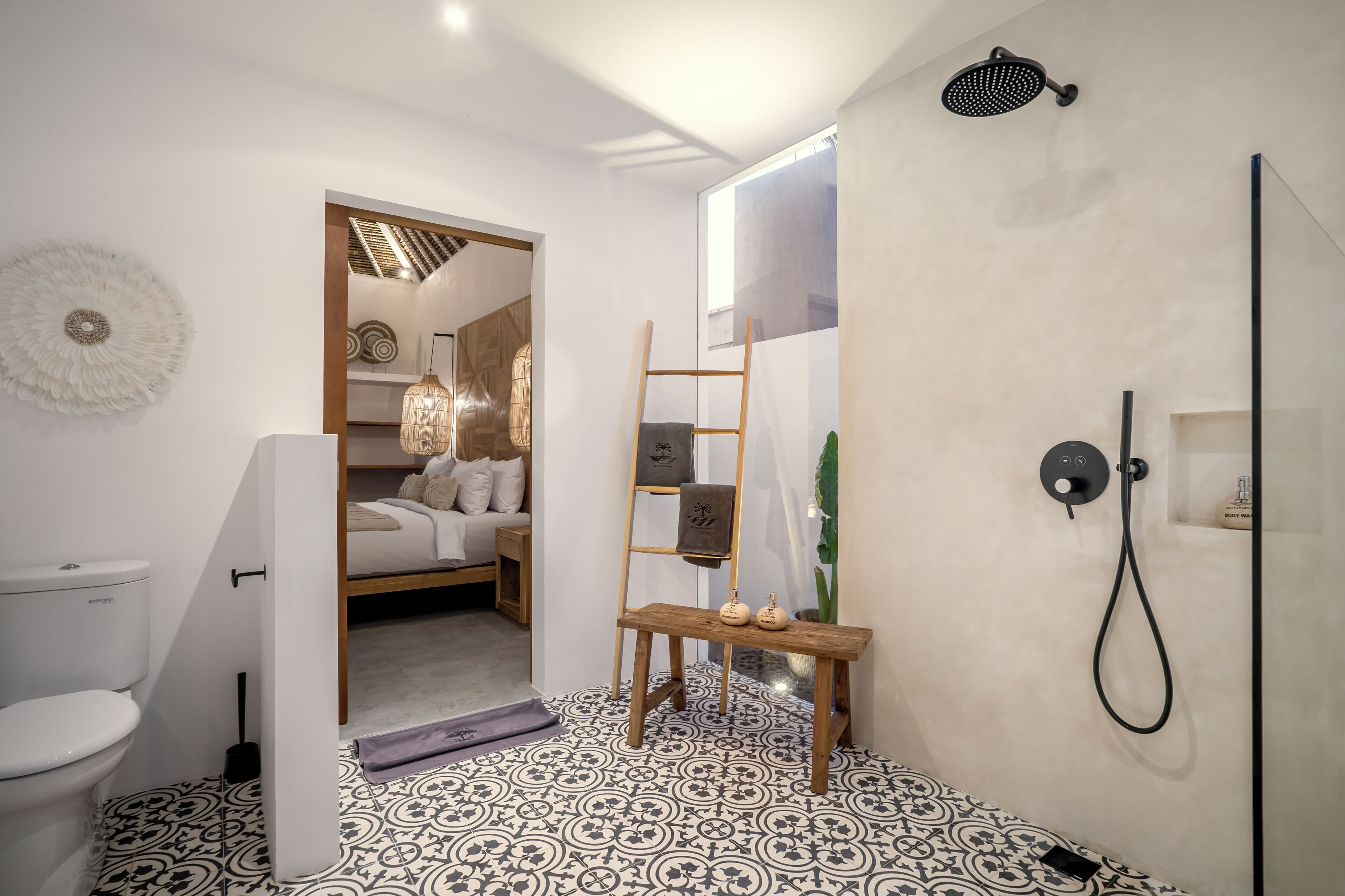 A modern bathroom with a shower, toilet, and a small wooden bench with decorative items.