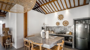 Une cuisine moderne dotée d’un grand îlot central, de chaises en bois et d’un luminaire suspendu.