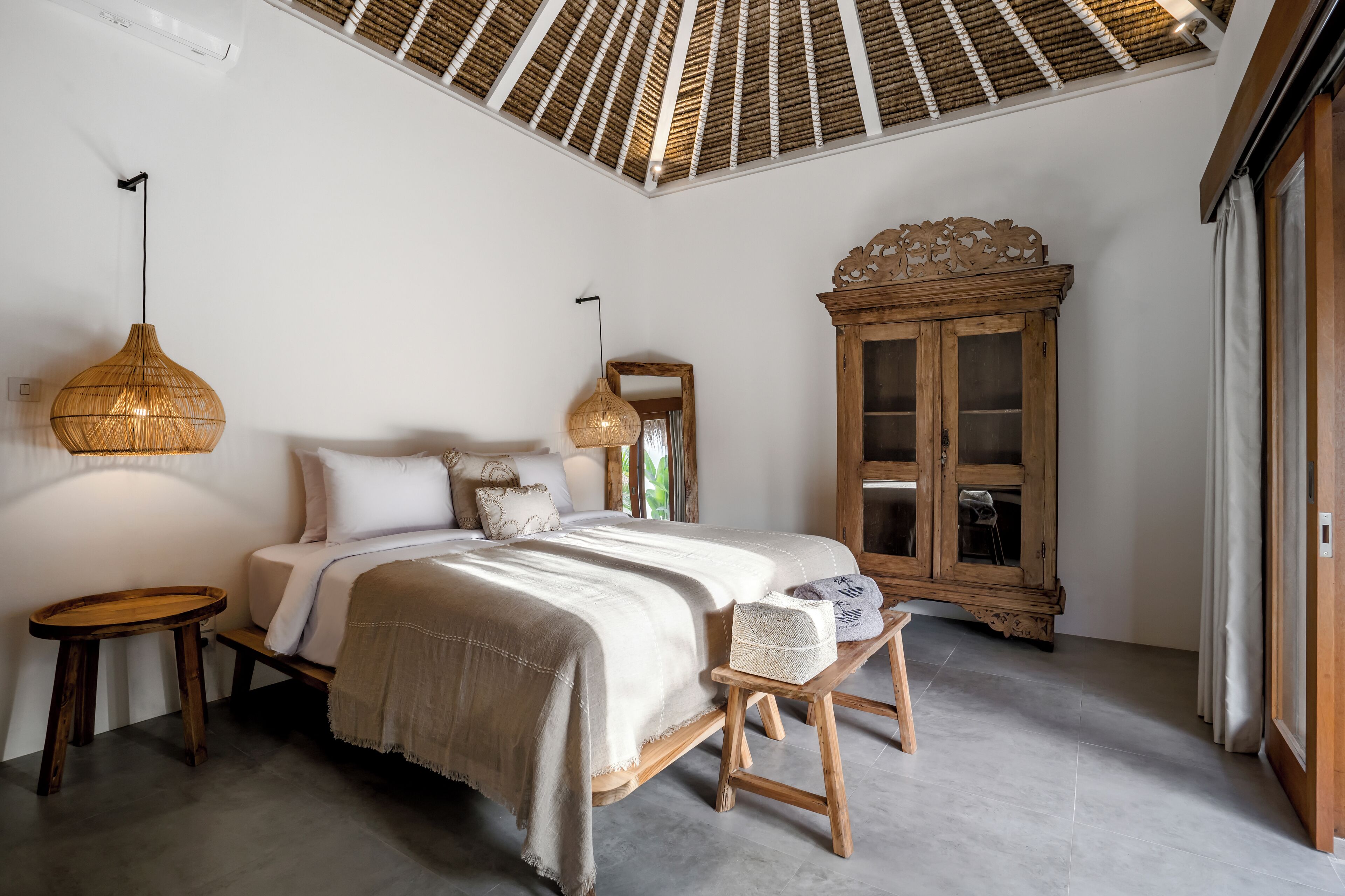 Une chambre à coucher comprenant un lit, des tables de chevet, une armoire en bois et un ventilateur de plafond.