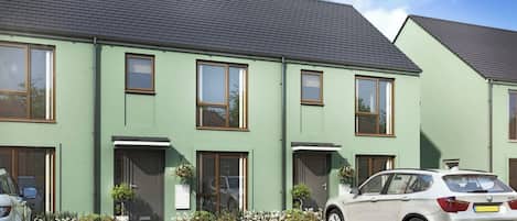 A row of modern, two-story houses with a green facade and dark roofs.