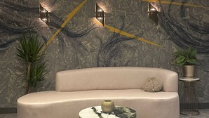 Uma sala de estar moderna com um sofá curvo, uma mesa de centro redonda e arandelas decorativas.