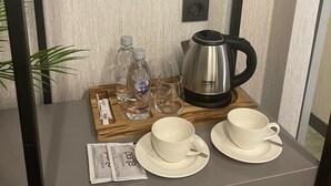 Uma pequena mesa com uma cafeteira, duas chávenas, dois copos e uma garrafa de água.