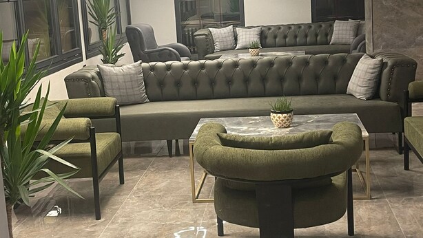 Uma sala de estar moderna com um sofá seccional, uma poltrona verde e uma mesa de centro.