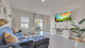 Ein modernes Wohnzimmer mit einem grauen Sofa, einem Couchtisch und einem an der Wand montierten Fernseher.