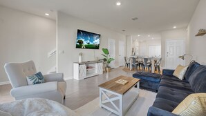 Ein modernes Wohnzimmer mit einer Couch, einem Couchtisch und einem an der Wand befestigten Fernseher.