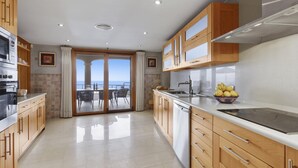A modern kitchen with wooden cabinets, a stainless steel sink, and a view to the outside. - Villa Luna Suites (Puigderrós)
