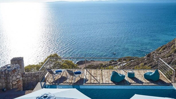 A poolside area with lounge chairs and a view of the sea. - Villa Luna Suites (Puigderrós)
