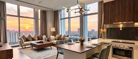 Una habitación de hotel moderna con un amplio ventanal, comedor, cocina y zona de estar con vistas a la ciudad.