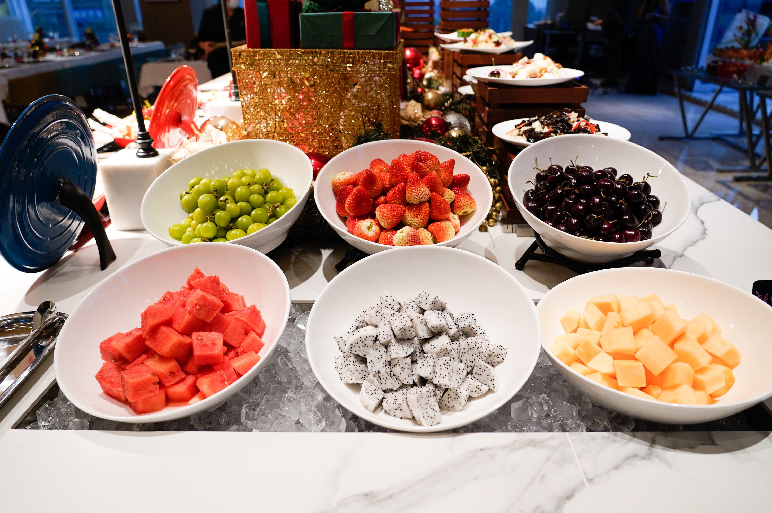 A table with various bowls of fruits and a gift box.