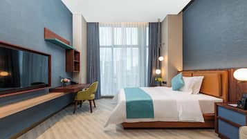Ein modernes Hotelzimmer mit einem großen Bett, einem Schreibtisch, einem Stuhl und einem Fernseher.
