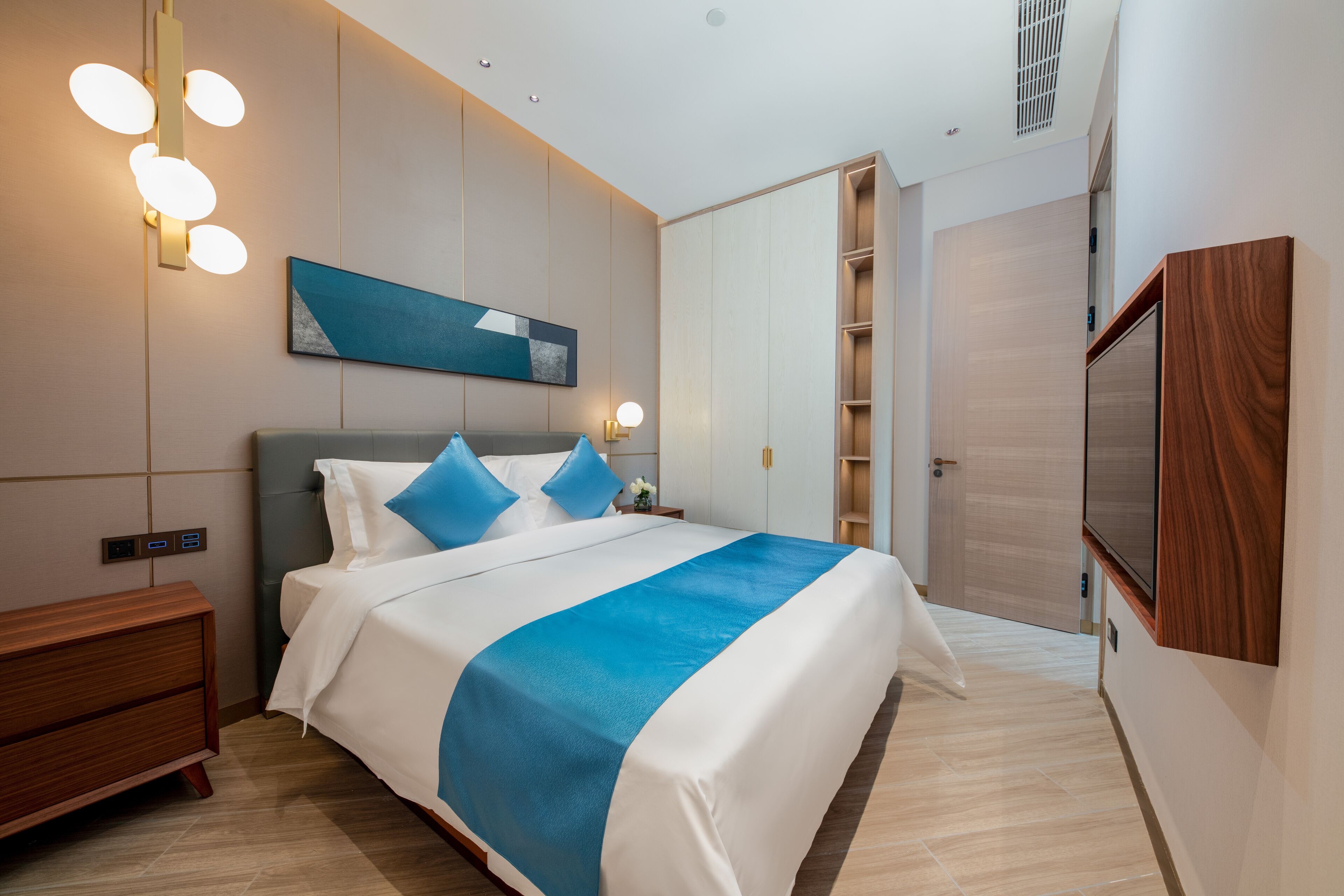 A modern hotel room with a large bed, bedside tables, a wardrobe, and a TV.