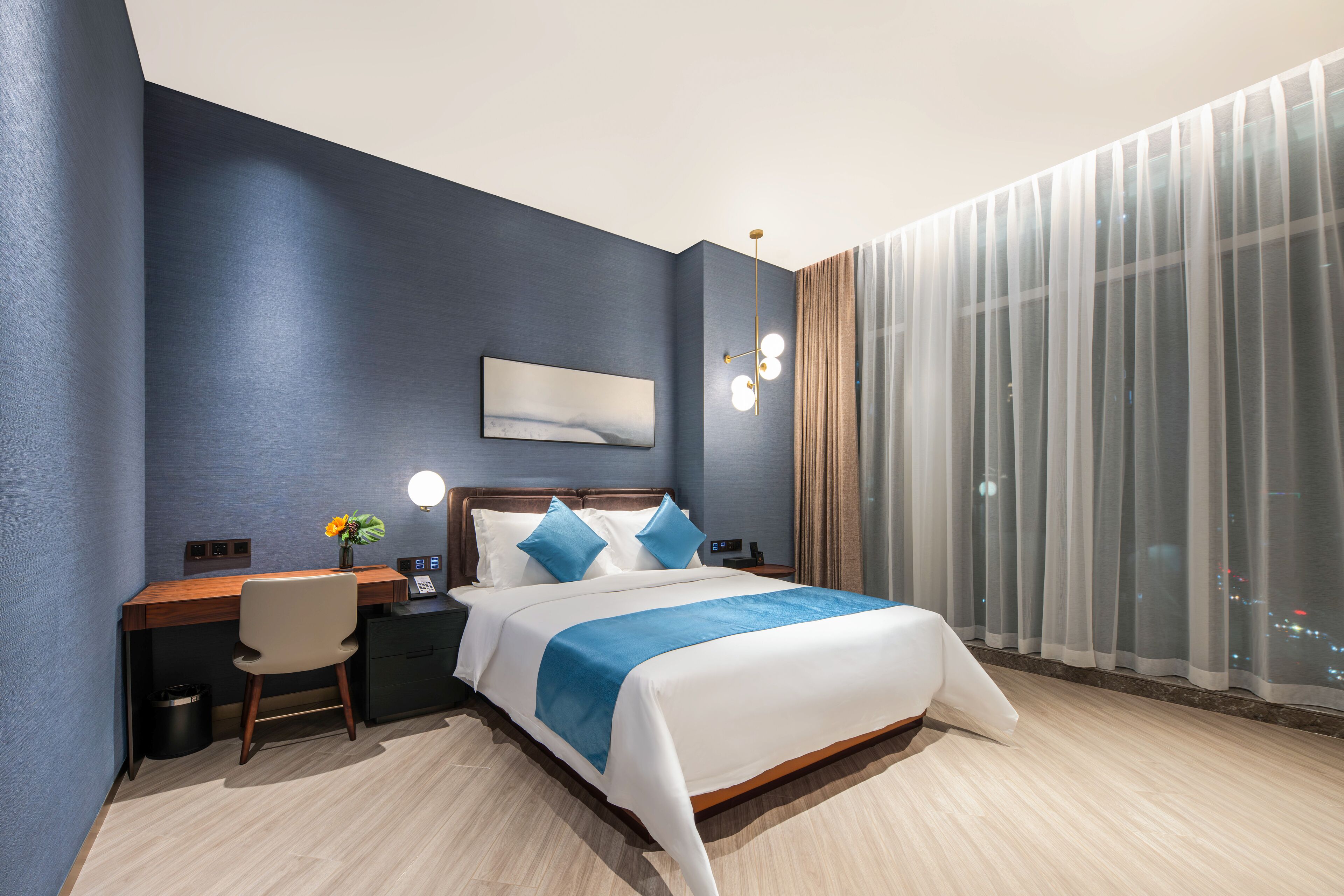 A modern hotel room with a large bed, a desk, and a chair.
