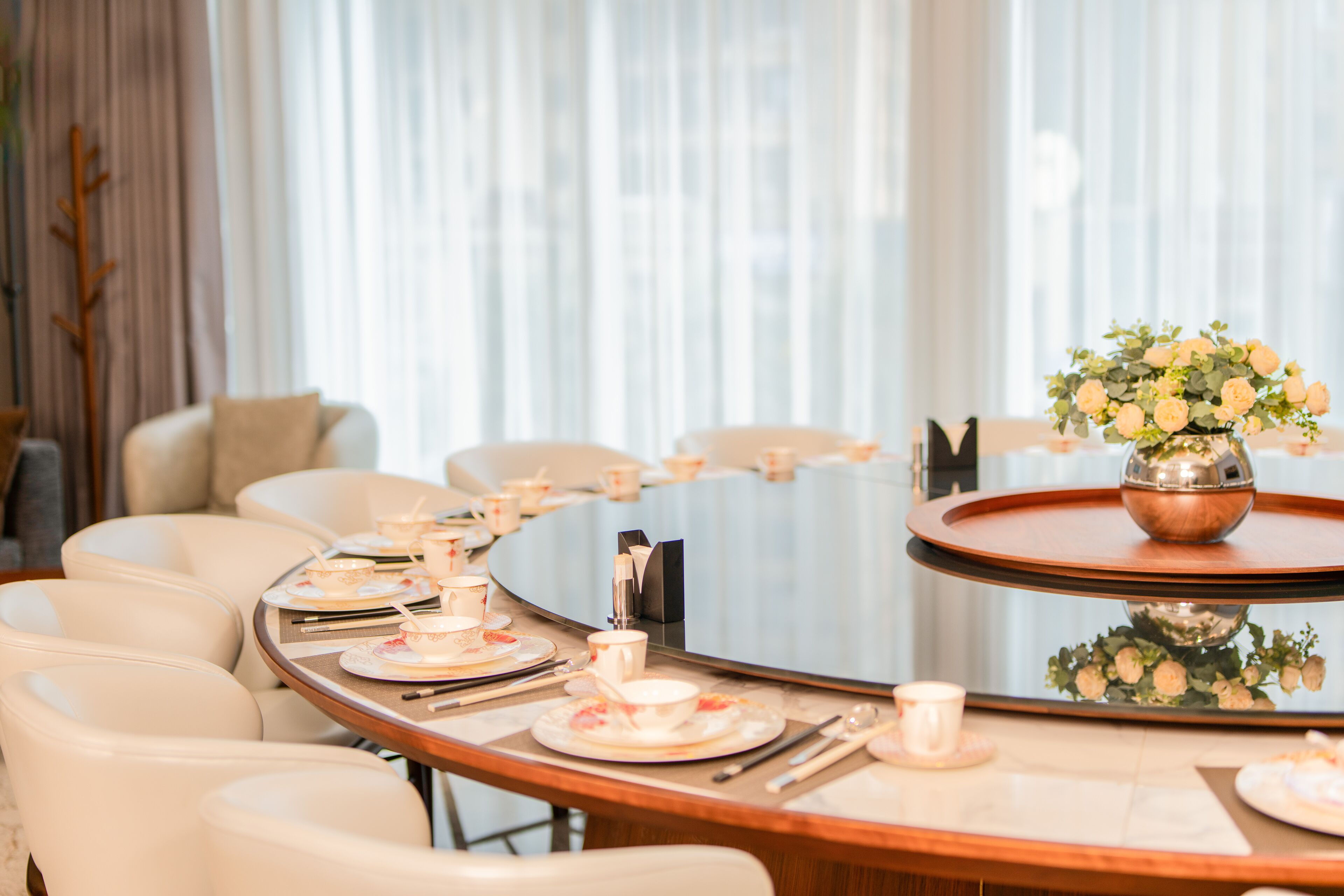 A dining area with a round table set for a meal, surrounded by chairs.