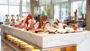 Ein reichhaltiges Buffet mit verschiedenen Speisen und Geschirr, einer Marmorplatte und einem Holzboden mit gestapelten Tellern.