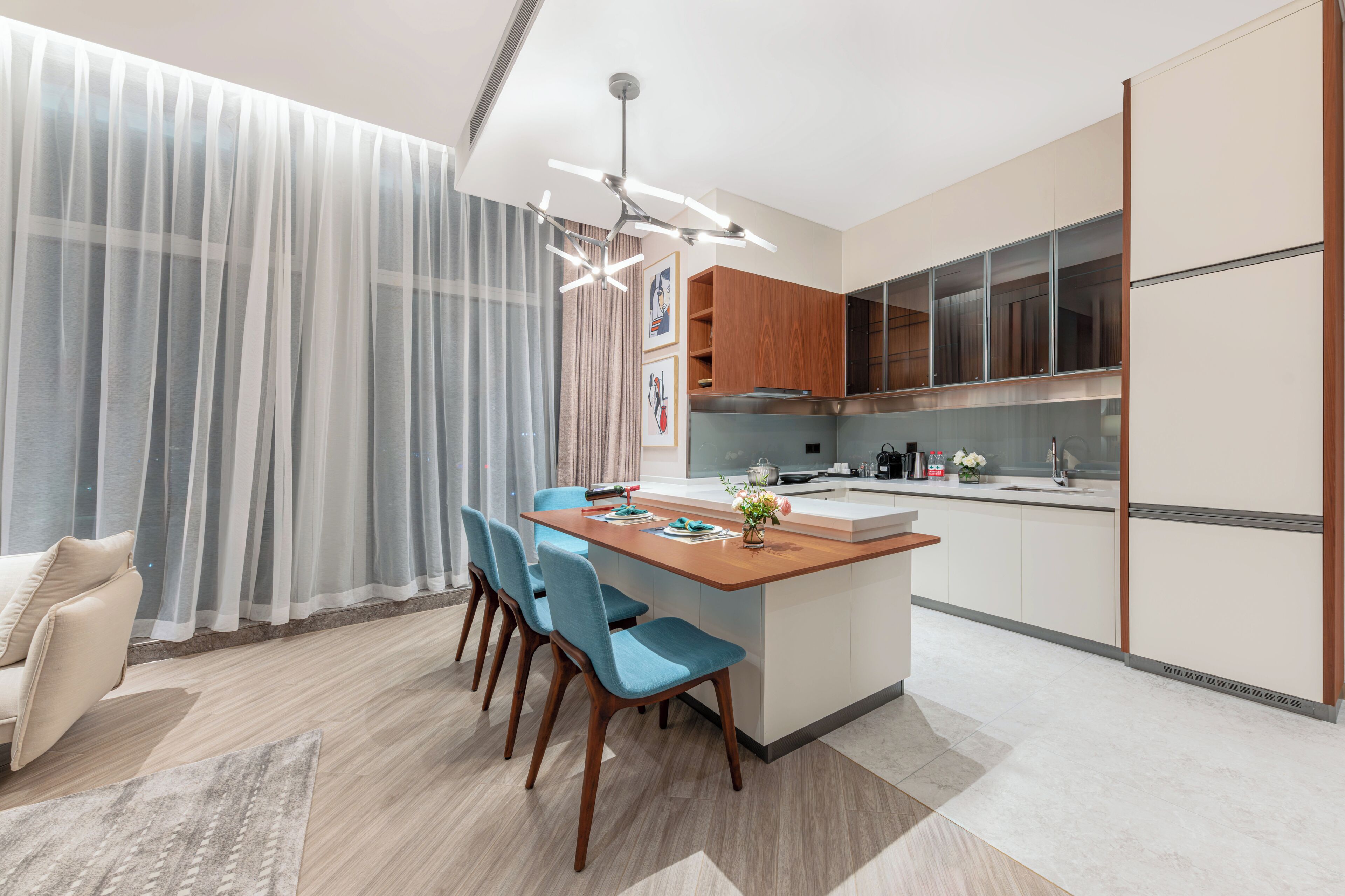 Una cocina moderna con una isla central, armarios de madera y una zona de comedor con sillas azules.