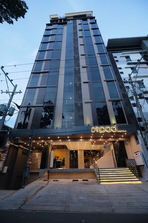 Un hotel moderno con una entrada destacada, una escalera y un letrero de neón.