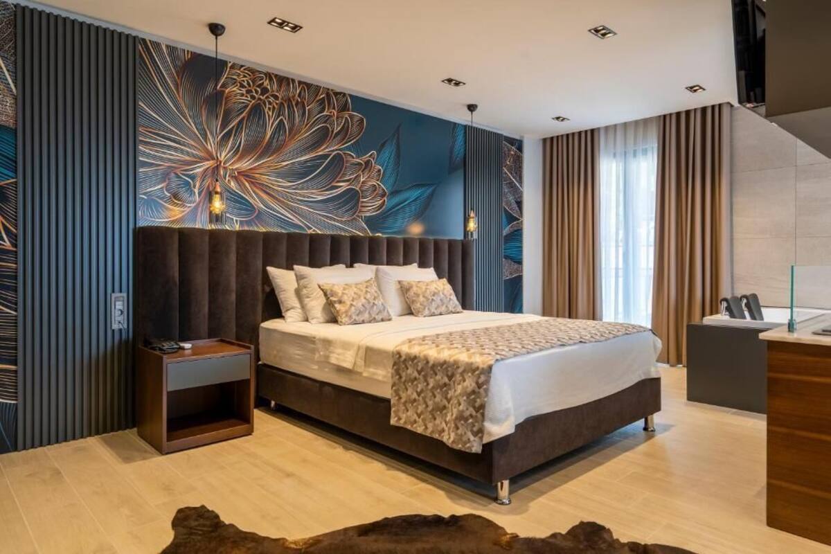 A modern bedroom with a large bed, a nightstand, a desk, and a decorative wall mural.