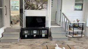 A living room with a fireplace, a TV, and a staircase leading to another room. - Luxury Camping at Calusa (Key Largo)