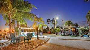 A beachside restaurant with outdoor seating, palm trees, and a food truck. - Luxury Camping at Calusa (Key Largo)