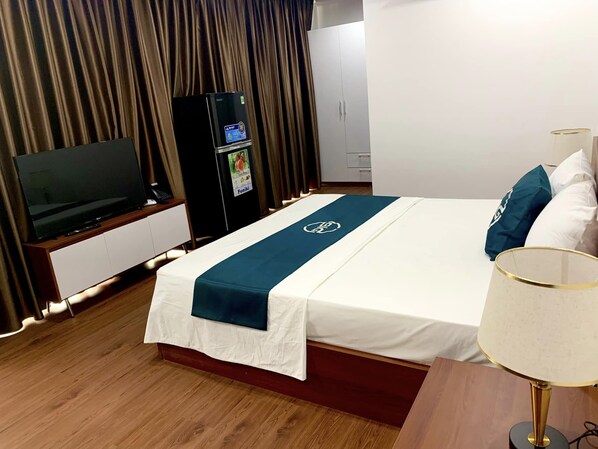 A hotel room with a bed, a TV, a minibar, and a wardrobe. - Big Hotel Lao Cai (Lao Cai)