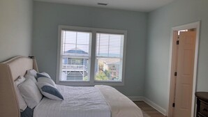 A bedroom with a bed, a ceiling fan, and a window with blinds. - Sun-kissed Mermaid / 846 Ocean Blvd West 2 Bedroom Home by RedAwning (Supply)