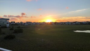 A sunset over a residential area with houses and a body of water. - Sun-kissed Mermaid / 846 Ocean Blvd West 2 Bedroom Home by RedAwning (Supply)