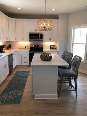 Enjoy cooking in this well-equipped kitchen with a central island, stainless steel microwave, and ample storage.