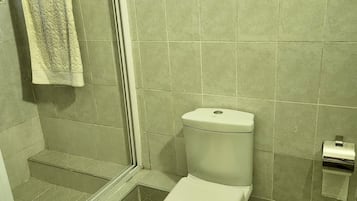 Une petite salle de bain comprenant des toilettes, un porte-serviettes et un distributeur de papier toilette.