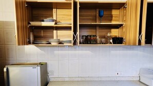 A compact kitchen with wooden cabinets, a double Sharp refrigerator, and a countertop with various kitchen items.