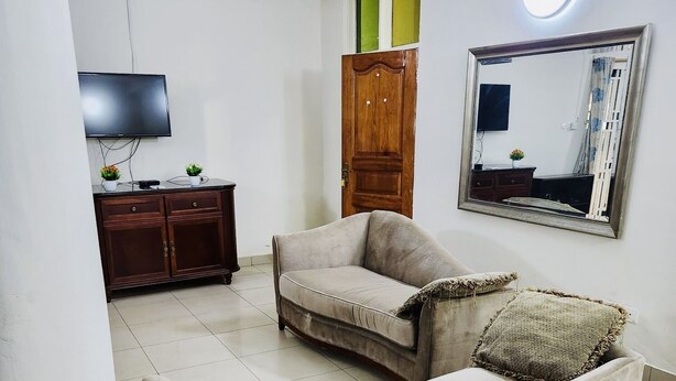 A living room with a sofa, a TV, a wooden cabinet, and a mirror.