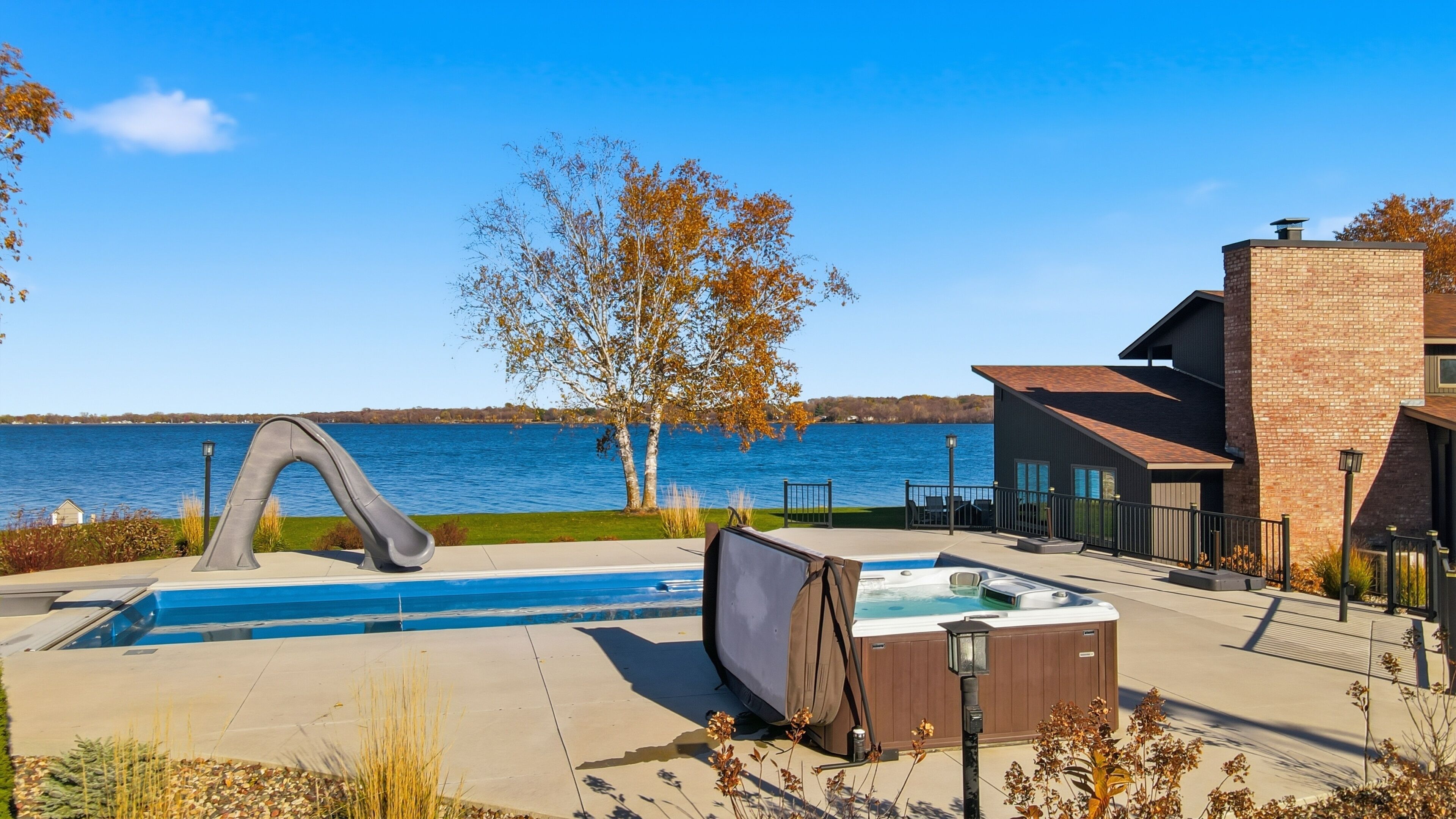 Ein Pool mit Rutsche, eine Whirlwanne und Blick auf einen See.