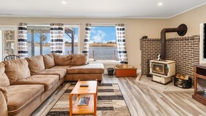 A living room with a sectional sofa, a small table, a fireplace, and a view of the water outside.