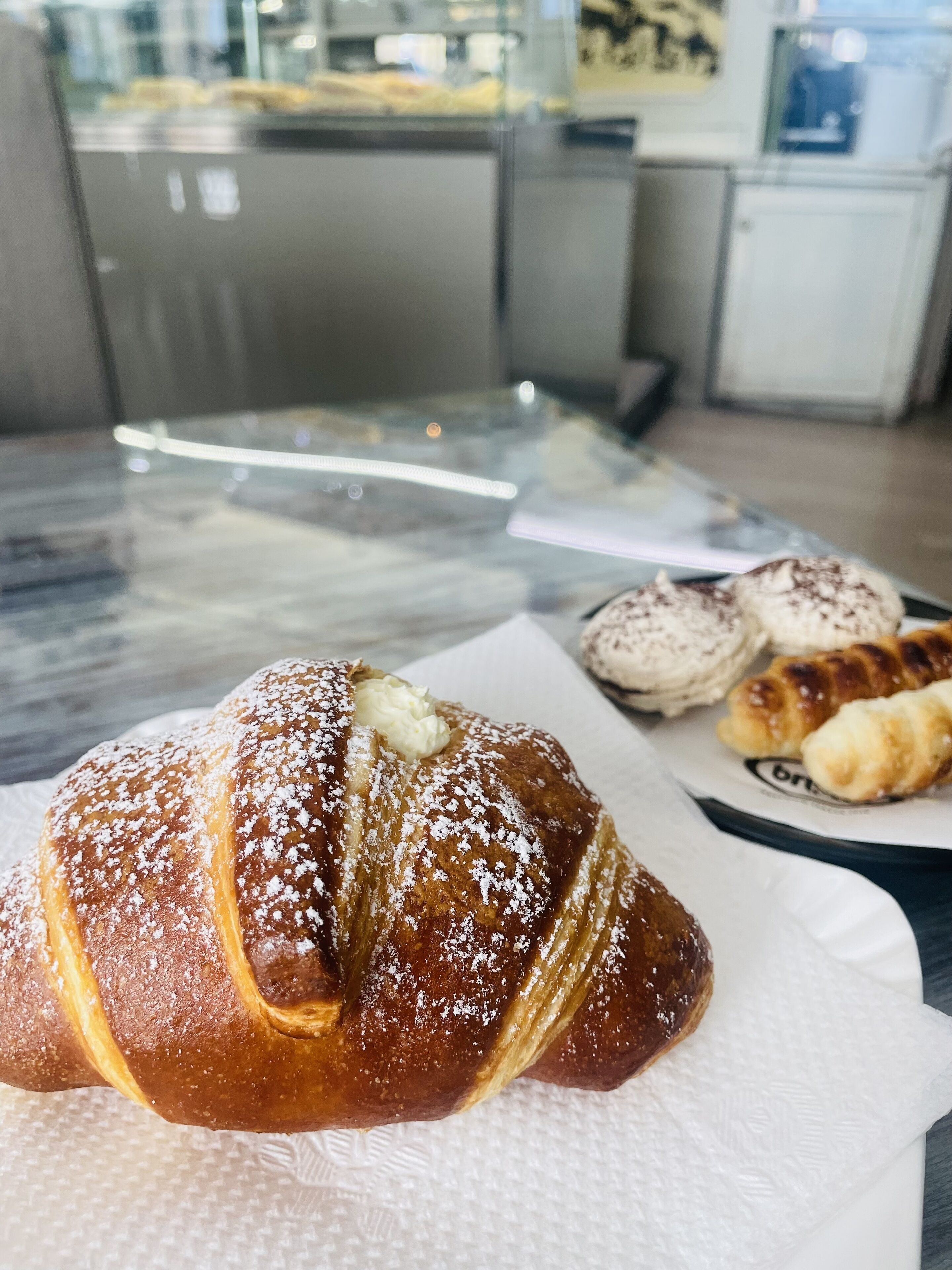 A croissant with powdered sugar and a pat of butter on a paper napkin.