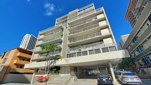 Un immeuble à plusieurs étages doté de balcons, d’une entrée sécurisée et de voitures garées.