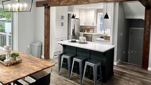 Una cucina moderna con isola centrale, sgabelli da bar e illuminazione a sospensione.