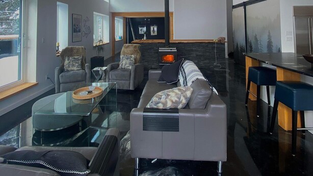 A modern living room with a glass coffee table, leather sofa, and a fireplace. - WhiskeyJack Estate (Revelstoke)