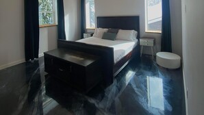 A modern bedroom with a wooden ceiling, a large bed, a bedside table, and a small stool. - WhiskeyJack Estate (Revelstoke)