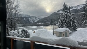 A snowy landscape with a river, mountains, and a small cabin. - WhiskeyJack Estate (Revelstoke)