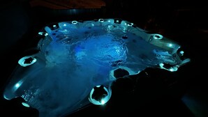A hot tub with a unique, organic design, illuminated by blue lights. - WhiskeyJack Estate (Revelstoke)
