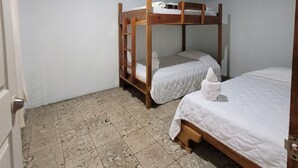 A room with two bunk beds, a door, and patterned floor tiles. - Hostel A lo Tico (Monte Verde)
