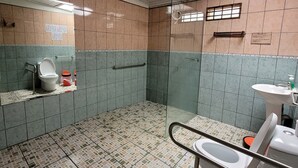 A bathroom with a tiled floor, a toilet, a sink, and a shower area. - Hostel A lo Tico (Monte Verde)