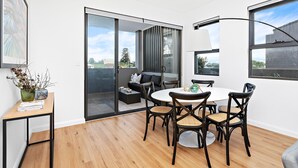 Een moderne eetruimte met een ronde tafel, zwarte stoelen en uitzicht door een schuifdeur op een buiten zitgedeelte.