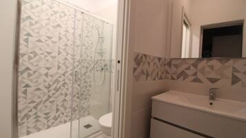 A bathroom with a shower, toilet, and sink.