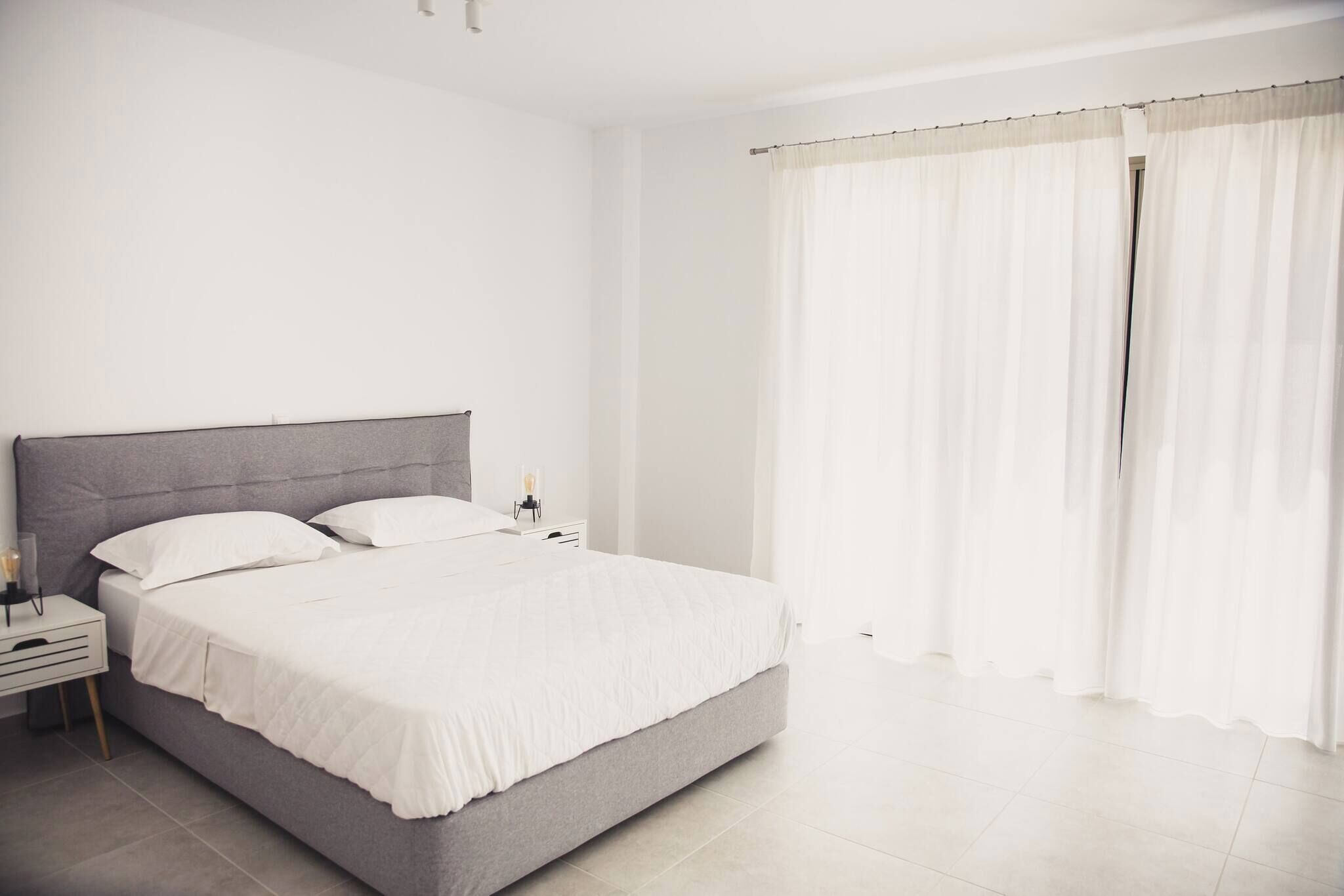 A bedroom with a bed, nightstand, and curtains.