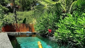 Un décor au bord de la piscine avec une table, deux verres, une bouteille de champagne et une fleur.